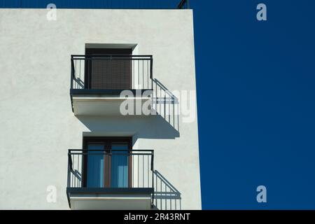 Façade de bâtiment moderne avec deux balcons et fenêtres avec roulettes. Volets roulants métalliques fermés et ouverts sur les fenêtres Banque D'Images