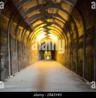 Arrière-plan flou avec un tunnel. Marche à travers le tunnel jusqu'à la lumière. Tunnel sombre. Banque D'Images