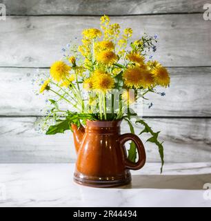 Encore la vie avec des pissenlits jaunes dans une théière sur une table en marbre blanc. Le concept est une vie saine et lumineuse. Banque D'Images