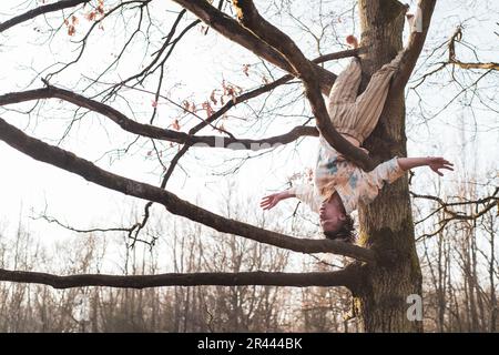 une danseuse étonnante se tient aux bras larges avec une grande liberté dans l'arbre Banque D'Images