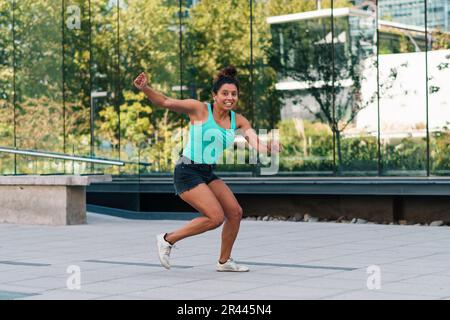 mignonne brune qui fait des coups de pied, des sauts et de la capoeira dans les rues Banque D'Images