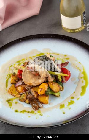 Crevettes enveloppées de bar sur divers légumes sur une assiette en porcelaine Banque D'Images