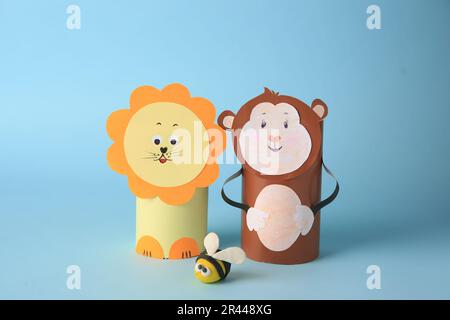 Singe jouet et lion en papier toilette hubs avec abeille plaline sur fond bleu clair. Idées faites à la main pour les enfants Banque D'Images