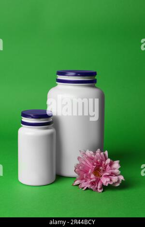 Bouteilles de médicaments et fleur rose sur fond vert. Médicament Banque D'Images