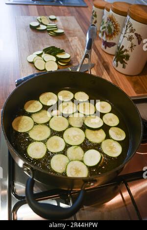 Friture ou brunissage de tranches de courgettes ou de courgettes dans de l'huile de tournesol prête à l'emploi dans un plat de pâtes italien Banque D'Images