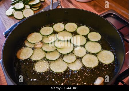 Friture ou brunissage de tranches de courgettes ou de courgettes dans de l'huile de tournesol prête à l'emploi dans un plat de pâtes italien Banque D'Images