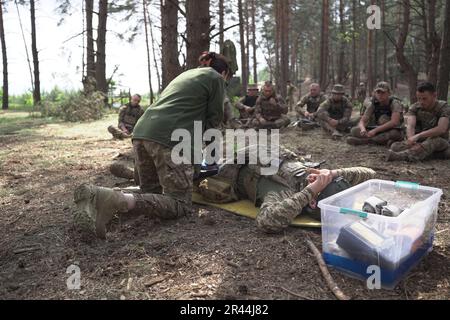 Les soldats de l'infanterie régulière des Forces armées de UkraineÕs reçoivent une formation médicale intensive de la part de bénévoles de la Fondation Prytula. Les formateurs de la fondation apprennent auprès d'experts en formation médicale occidentale de type OTAN au TCCC. Les soldats de la grande base militaire simulent les conditions de première ligne, vivent dans la forêt et creusent des tranchées sur de longues périodes. Banque D'Images