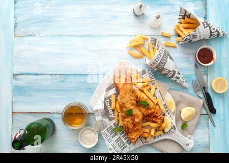 Plats traditionnels à emporter avec du poisson et des frites, emballés dans le journal avec de la bière Banque D'Images