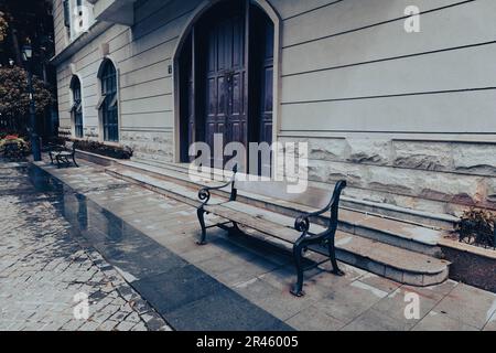 Un banc extérieur dans une cour en face d'un bâtiment blanc Banque D'Images