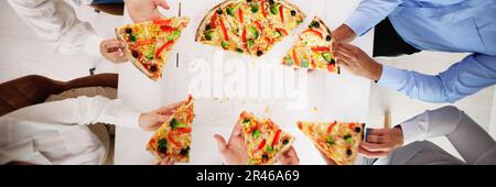 Amis manger de la pizza à la table de bureau à l'intérieur Banque D'Images