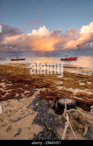 Vue panoramique de deux bateaux amarrés sur la rive d'une plage, illuminés par les couleurs chaudes du soleil couchant Banque D'Images