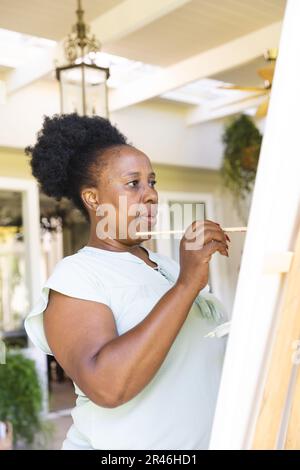 Focalisé bonne femme afro-américaine senior peinture toile sur chevalet à la maison Banque D'Images