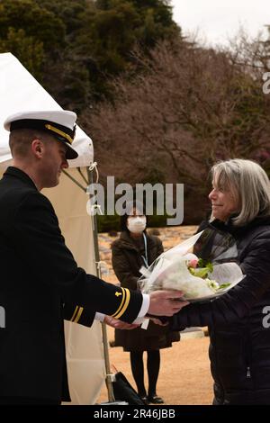 YOKOHAMA, Japon (14 février 2023) Lt. j.g. Nicolas Tobin, États-Unis L'aumônier d'état-major de la Marine, affecté au commandant des activités de la flotte Yokosuka, remet des fleurs à un membre de la famille vétéran lors d'une cérémonie commémorative de guerre pour le programme d'amitié des Japonais/prisonniers de guerre, le 14 février, au cimetière de guerre du Commonwealth de Yokohama. Le cimetière comprend une importante urne contenant les cendres de 335 marins, soldats et aviateurs des États-Unis, du Commonwealth britannique et du Royaume des pays-Bas, qui sont morts comme prisonniers de guerre au Japon. La cérémonie est parrainée par le ministère des Affaires étrangères et commandant de la région navale de Ja Banque D'Images