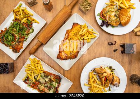 Un ensemble de plats avec des milanesas assortis cuits au four avec un plat de frites Banque D'Images