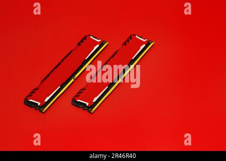 Certains modules de mémoire RAM croisés de DDR4 avec dissipateurs de chaleur métalliques rouges sur une surface rouge lisse Banque D'Images