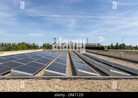 Alignement de panneaux solaires récemment installés sur le toit d'un immeuble de bureaux Banque D'Images