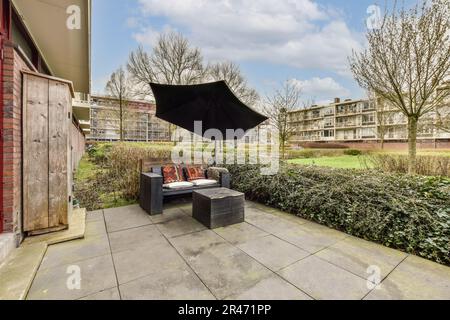 un patio avec un parasol au-dessus de la cheminée et quelques buissons dans la cour arrière, par une journée ensoleillée Banque D'Images