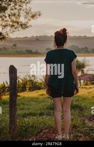 jeune femme de l'arrière regardant le coucher du soleil Banque D'Images