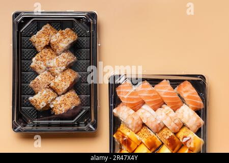 Un ensemble de petits pains à sushis dans des emballages en plastique à emporter sur un fond clair, vue du dessus. Livraison de sushis dans un contenant en plastique Banque D'Images
