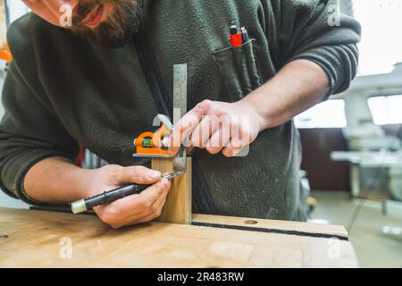 Mains de menuisier mâle ligne de dessin à l'aide d'un marqueur et d'une règle avant de couper le bois. Photo de haute qualité Banque D'Images