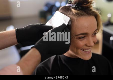 Mains de caucasien homme coiffeur teinture cheveux de sourire femme client au salon Banque D'Images