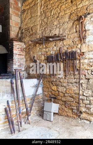 Ancien ensemble d'outils pour forgeron à côté d'une forge. Banque D'Images