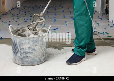 Homme mélangeant de l'adhésif pour carreaux à l'intérieur, vue rapprochée Banque D'Images