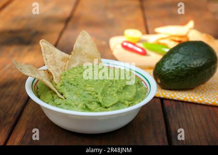 Délicieux guacamole fait d'avocats avec nachos sur table en bois Banque D'Images