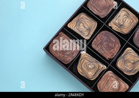 Boîte de bonbons au chocolat savoureux sur fond bleu clair, vue de dessus. Espace pour le texte Banque D'Images