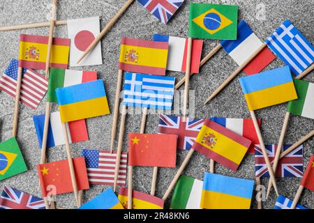 De nombreux petits drapeaux en papier de différents pays sur table grise, à plat Banque D'Images