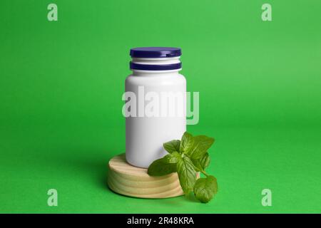 Bouteille de médecine en plastique et feuilles sur fond vert. Médicament Banque D'Images