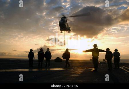 LES directeurs d'aéronefs DE la MARINE AMÉRICAINE guident un hélicoptère en position sur le pont de vol du navire Banque D'Images