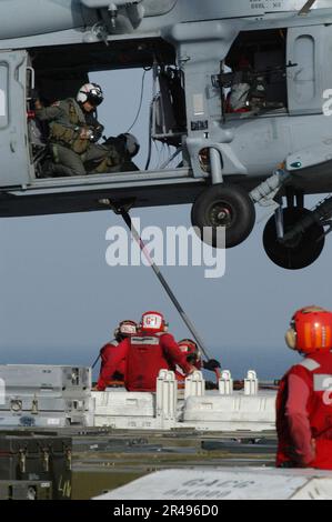 LES soldats DE l'aviation DE LA MARINE AMÉRICAINE à bord de l'USS Abraham Lincoln (CVN 72) connectent un poteau de boucle de charge à une HNighthawk MH-60s Banque D'Images