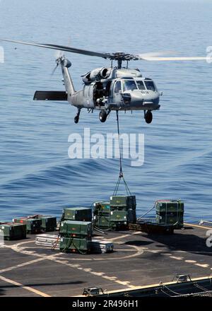 MARINE AMÉRICAINE un Chevalier MH-60s livre une caisse d'ordnance au Commandement militaire de l'ascenseur de la mer, navire de munitions USNS Kiska (T-AE 35) pendant un transfert d'armes de l'USS Abraham Lincoln (CVN 72) Banque D'Images