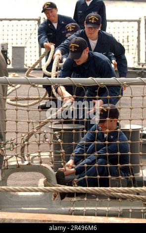 LES marins DE la Marine AMÉRICAINE à bord de l'USS Curtis Wilbur (DDG 54) tirent dans l'une de ses lignes d'amarrage après être revenu d'un travail en mer Banque D'Images