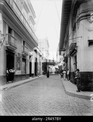 Rue de la Havane, la Havane, C1900. La photo montre l'intersection avec la rue Obrapia (plaque d'identification sur le bâtiment de droite). Le panneau suspendu de l'autre côté de la rue indique « Bazar Ingles ». (Source : Roberto Duarte, 2013) Banque D'Images