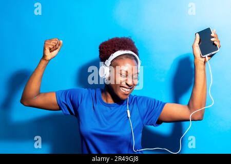 Portrait d'une jeune femme noire gaie qui écoute de la musique avec un casque Banque D'Images
