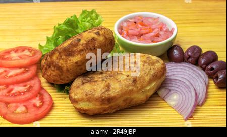 Une assiette remplie d'ingrédients, y compris des pommes de terre, de la laitue, des tomates et d'autres légumes Banque D'Images