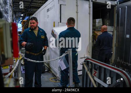 LES marins DE SINGAPOUR (14 mars 2023) déplacent les fournitures et les produits congelés dans le conteneur de congélation pendant un chargement de magasins à bord du navire de combat littoral de la classe Independence USS Oakland (LCS 24) à la base navale de Changi, Singapour, 14 mars 2023. Oakland, qui fait partie de l'escadron 7 de Destroyer, est en cours de déploiement par rotation, opérant dans la zone d'opérations de la flotte américaine 7th afin d'améliorer l'interopérabilité avec les alliés et les partenaires et de servir de force d'intervention en appui à une région Indo-Pacifique libre et ouverte. Banque D'Images