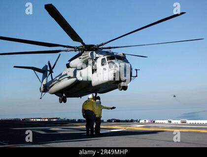 LES mates DE Boatswain DE L'AVIATION DE LA MARINE AMÉRICAINE dirigent un CH-53E « sea Stallion » lorsqu'il manœuvre pour atterrir sur le pont de vol du navire Banque D'Images