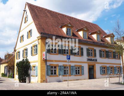 Bâtiment résidentiel de deux étages avec toit en carreaux rouges et fenêtres peintes en jaune dans une ville Banque D'Images