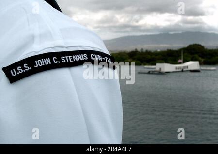 US Navy A Sailor a les rails comme le porte-avions de la classe Nimitz USS John C. Stennis (CVN 74) passe devant le USS Arizona Memorial Banque D'Images