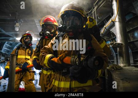 LES marins DE SINGAPOUR (15 mars 2023) exploitent un boyau d'incendie lors d'un exercice de contrôle des dégâts à bord du navire de combat littoral de classe Independence USS Oakland (LCS 24) à la base navale de Changi, Singapour, 15 mars 2023. Oakland, qui fait partie de l'escadron 7 de Destroyer, est en cours de déploiement par rotation, opérant dans la zone d'opérations de la flotte américaine 7th afin d'améliorer l'interopérabilité avec les alliés et les partenaires et de servir de force d'intervention en appui à une région Indo-Pacifique libre et ouverte. Banque D'Images