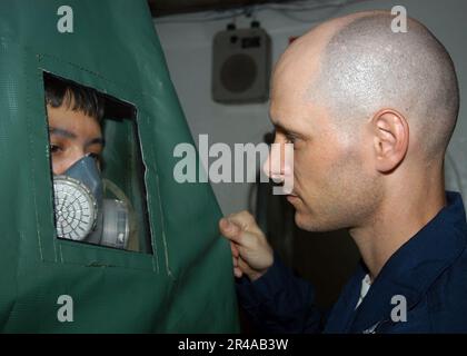 LA classe US Navy Machinist Mate 1st attribuée au service de sécurité, effectue un test d'ajustement sur un Sailor pour un respirateur à bord du transporteur d'avions à puissance conventionnelle USS John F. Kennedy (C Banque D'Images