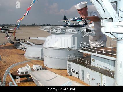 US Navy Engineman 1st Class ajuste un modèle de OS2U hydravion Kingfisher à bord d'un modèle à grande échelle du navire de guerre Nevada (BB 36) Banque D'Images