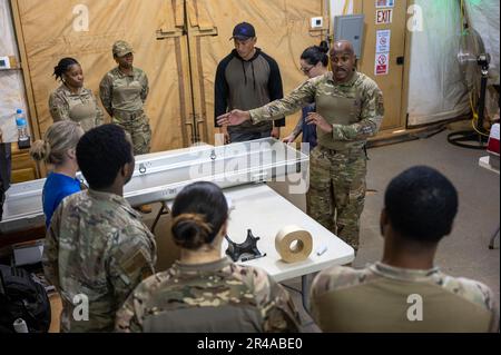 Les aviateurs de l'escadron de la base aérienne expéditionnaire 768th, vol de services, discutent de l'utilisation de la boîte de transfert de restes humains pendant l'entraînement aux affaires mortuaires à l'AB 101, Niger, 4 avril 2023. Des aviateurs formés à prendre soin du membre du service décédé, notamment en portant correctement la boîte de transfert des restes humains et en drageant le drapeau. Banque D'Images