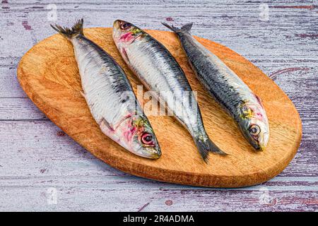 Un gros plan de trois sardines sur une planche de bois. Banque D'Images