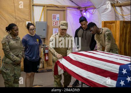 Les aviateurs de l'escadron de la base aérienne expéditionnaire 768th, vol de services, s'entraînent à drapier correctement un drapeau américain au-dessus d'un cas de transfert de restes humains pendant l'entraînement des affaires mortuaires à l'AB 101, Niger, 4 avril 2023. Des aviateurs formés à prendre soin du membre du service décédé, notamment en portant correctement la boîte de transfert des restes humains et en drageant le drapeau. Banque D'Images