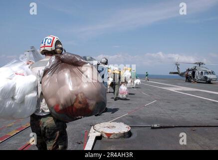 LES marins DE la Marine AMÉRICAINE attendent de charger des sacs de jouets sur un hélicoptère Seahawk HH-60H affecté au 2e Escadron anti-sous-marin de Golden Falcons of Helicopter (HS-2) Banque D'Images