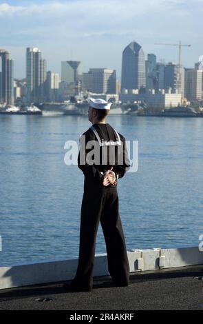 MARINE AMÉRICAINE Un marin affecté au porte-avions de classe Nimitz USS Carl Vinson (CVN 70), est aux rails lorsque le navire quitte la base navale de San Diego, en Californie, pour un déploiement régulier Banque D'Images